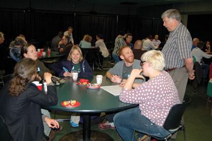 man talking to table of people